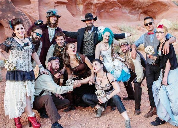 Group photo of steampunk bride and groom and wedding guests posing in the desert