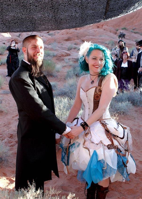 Bearded groom and steampunk bride holding hands while taking wedding vows