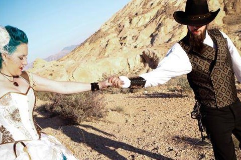 Newly married couple walking across the desert holding hands