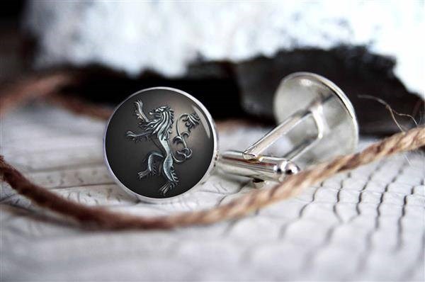 Silver cufflinks with house of Lannister sigil, lying on a table