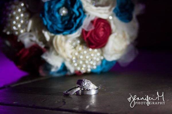 Wedding rings with bridal bouquet in the background