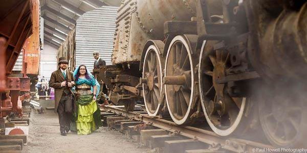 Steampunk bride and groom alongside locomotive train