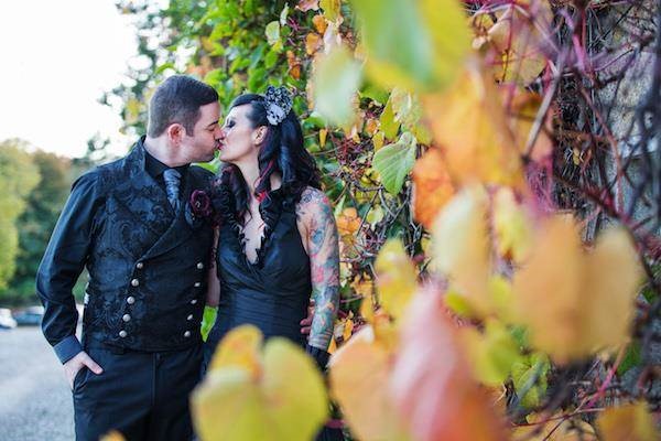 Gothic bride and groom kiss after their Halloween wedding