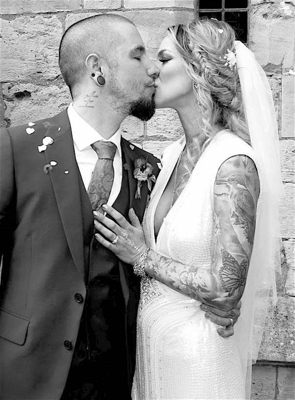 Tattooed bride and groom stealing a kiss.